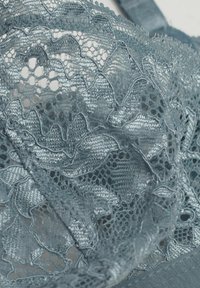Kantenn jaar in gedempt blauw met ingewikkelde golvende patronen, delicate gaasstructuur en gladde randen met zachte verstelbare bandjes.