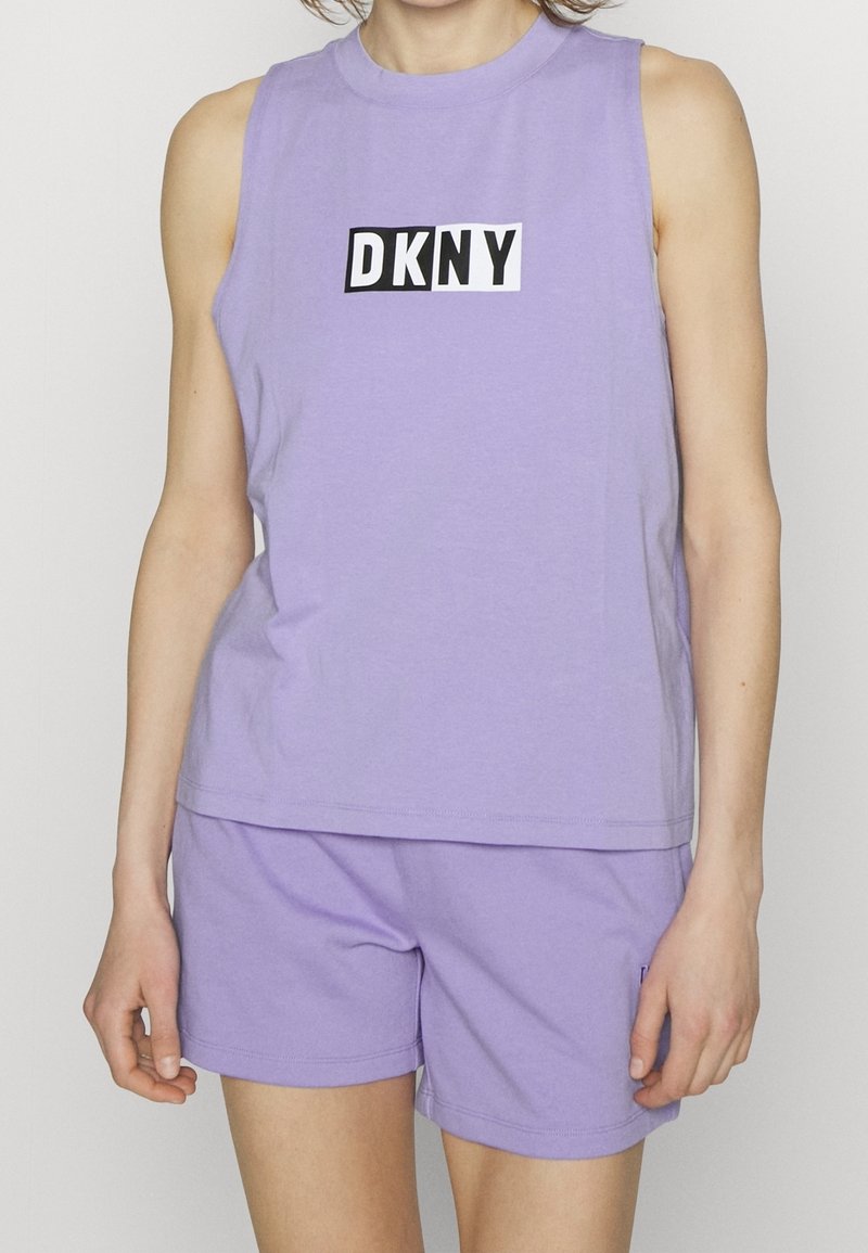 Canotta di cotone lavanda con scollatura rotonda e maniche a spalla, caratterizzata da un logo "DKNY" in bianco e nero sul davanti. Abbinata a pantaloni corti coordinati.