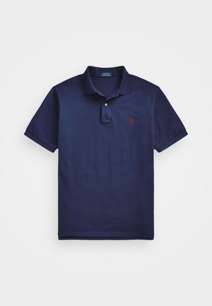 Polo de color azul marino hecho de algodón, con un cierre de dos botones y un pequeño logo rojo en el pecho. Textura suave, mangas cortas.