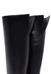 Bottes noires en cuir, arrivant au genou, avec une texture lisse, une forme arrondie et un haut évasé. Présentent des coutures propres et aucun matériel visible.