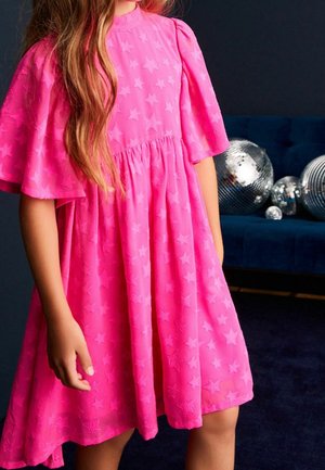 Robe rose à motifs d'étoiles avec manches courtes bouffantes, dotée d'une taille froncée et d'une jupe fluide. Tissu doux et texturé ajoutant de la finesse.