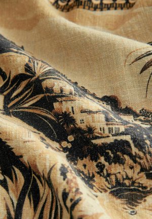 Lätt tyg med en beige bakgrund och ett svart botaniskt mönster samt detaljerade landskapselement, inklusive hus och växtlighet.