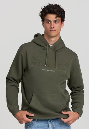 Felpa verde con tasca a marsupio, caratterizzata da testo in rilievo "BR.AKER" e "SELF BELIEVER" in bianco. Tessuto morbido e cappuccio regolabile con cordino.