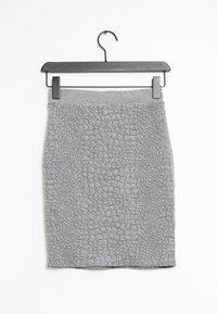 Jupe texturée grise au design ajusté, avec un motif de type bulle, suspendue à un cintre en métal noir sur fond blanc.