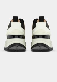 Μαζεμένα αθλητικά παπούτσια με επάνω μέρος σε μαύρο και κρεμ, με λεία μαύρη σόλα και διακριτικές αντίθετες ταμπά λεπτομέρειες στη φτέρνα.