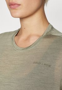 Alyvuogių žalios spalvos, lengvas marškinėliai su apvalia iškirpte. Yra subtilus ODLO x POW ženklas ant medžiagos, kuri yra glotni, šiek tiek tekstūruota.