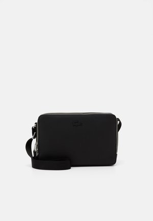 Sac bandoulière rectangulaire en cuir noir avec finition texturée, fermeture éclair argentée, bandoulière réglable et petit logo embossé au centre avant.