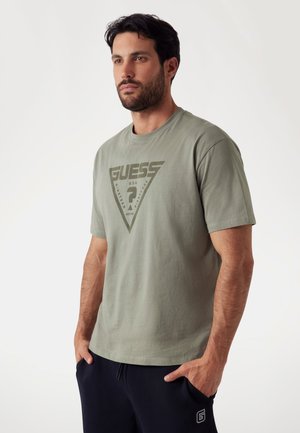 Olive green cotton t-shirt with short sleeves, featuring a large triangular logo and text design in darker green at the front.