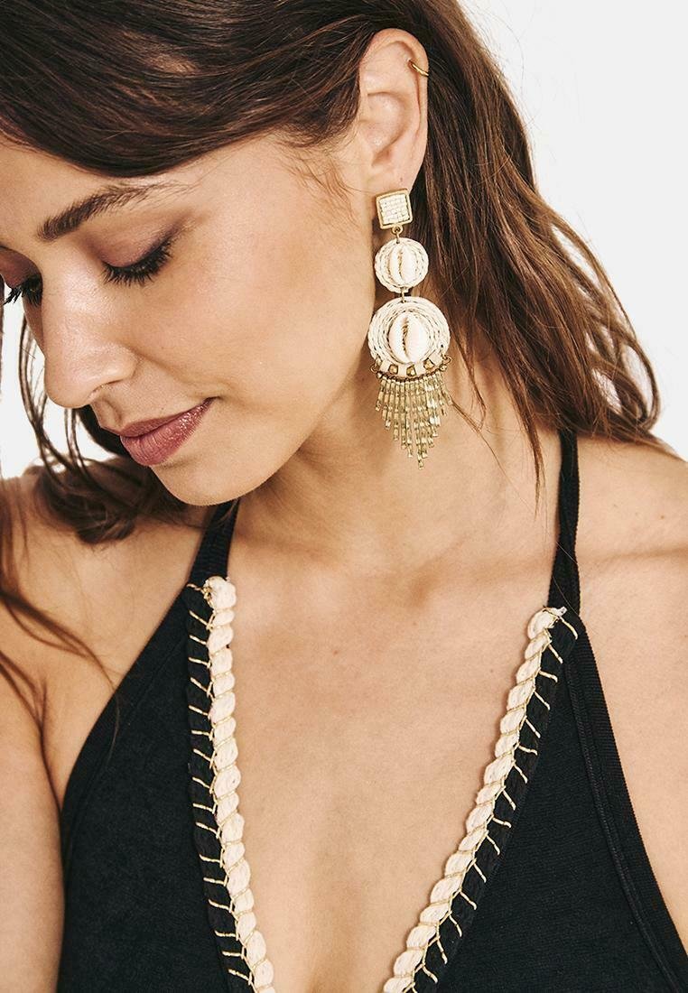 Pendientes de oro y crema con discos redondos texturizados y cadenas colgantes para un detalle adicional. Diseñados de manera única con acentos geométricos.