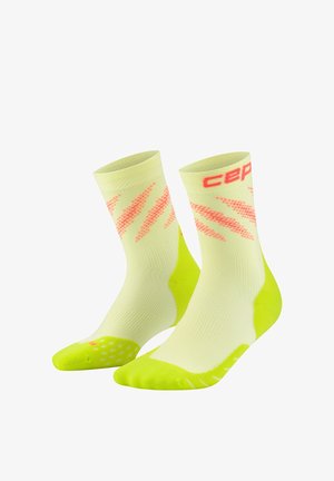 Gelbe und neongrüne sportliche Kniestrümpfe mit pinken diagonalen Streifen und roter "CEP"-Markierung Nähe des oberen Bündchens, seitlich geneigt auf weißem Hintergrund.