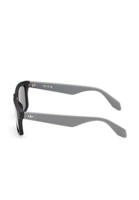 Occhiali da sole neri e grigi con montatura rettangolare, lenti semitrasparenti e aste grigie testurizzate con un motivo a spina di pesce.