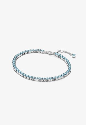 Bracciale d'argento con gemme blu chiaro incastonate in un design a artiglio. Dotato di una chiusura e una catena regolabile con un piccolo charm abbinato.