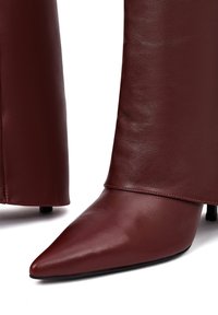 Bordeaux leren enkellaars met een spitse neus, gladde textuur en slanke stilettohak; heeft een strakke schacht met een nette naad.