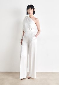 White satin jumpsuit with one shoulder design, wide legs, and side pockets. The fabric has a smooth, glossy texture.