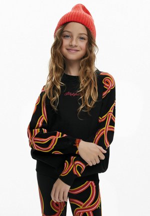 Schwarzer Sweatshirt mit bunten Wirbelmustern in Rot, Gelb und Orange an den Ärmeln, kombiniert mit passenden Leggings und einer leuchtend roten Mütze.
