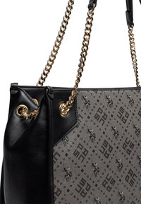 Svart läder och gråmönstrad canvashandväska med kedjestraps i guldton och öglor; har diskret branding och texturerade ytor.