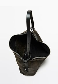 Borsa tote in suede aperta con tracolla regolabile in pelle nera e zipper argentato su sfondo bianco.