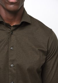 Mörk olivgrön knapp-up skjorta, mjukt tyg, klassisk krage, sex knappar, slät textur, nära passform, minimalistisk design.