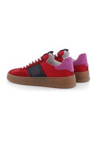 Sneakers rossi in suede con accenti neri e lacci bianchi. Presentano un tab sul tallone rosa e una suola in gomma spessa marrone. Design minimalista.
