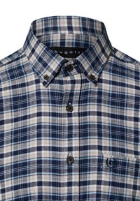 Camicia a quadri blu e beige con colletto abbottonato, taschino sul petto e bottoni scuri. Realizzata in tessuto intrecciato con una finitura testurizzata.