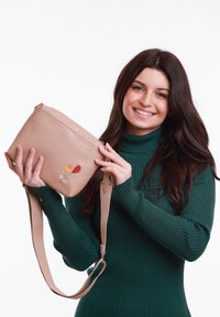 Beige crossbody taška z kůže, zdobená květinovou výšivkou v žluté, růžové a červené barvě. Obsahuje dlouhý nastavitelný popruh a zipové zapínání.