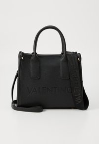 Black textured handbag with dual top handles, detachable shoulder strap, embossed branding, and gold-tone hardware accents.
