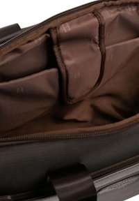 Brown interior of a bag with padded compartments and a smooth texture. Features a zippered closure and subtle patterned lining.
