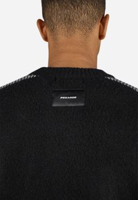 Black knit sweater with a textured finish, featuring a round neck and a black label with the brand "PEGADOR" at the back neckline.