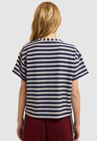 Top de manga corta a rayas en azul marino y plateado con un corte holgado y cuello redondo, fabricado en un material texturizado y ligeramente brillante.