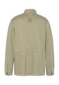 Giacca khaki con colletto rialzato, polsini abbottonati e vita elastica. Presenta un logo ricamato sulla parte alta della schiena e una texture liscia.