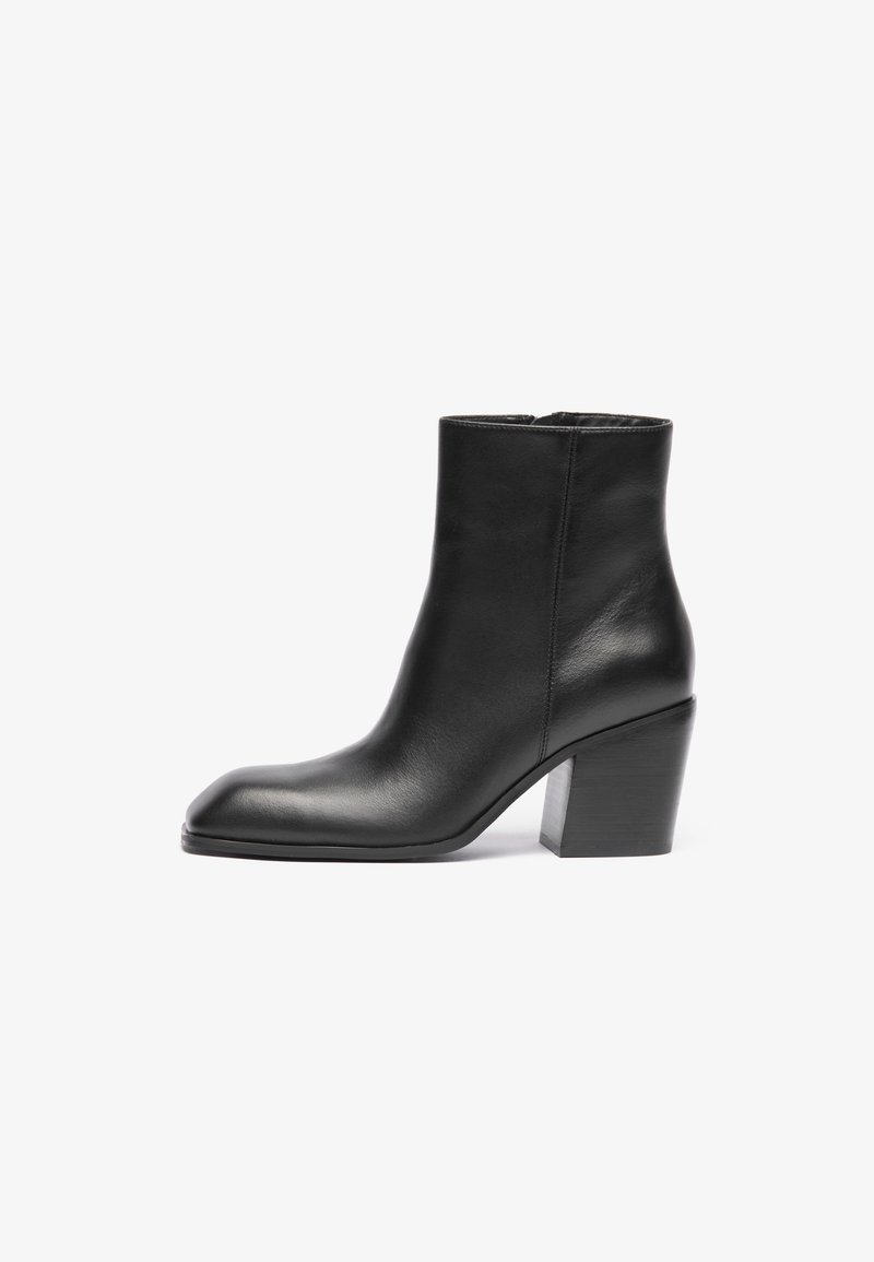 Cizmă neagră din piele până la gleznă, cu vârful pătrat și toc bloc masiv. Textură netedă și design minimalist. fermoar lateral pentru o purtare ușoară.