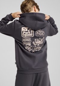 Sudadera con capucha de color gris oscuro con un gran estampado gráfico en la espalda que presenta varios logotipos de "Park Squad" en un tono beige claro. Cuenta con capucha con cordones y puños acanalados.
