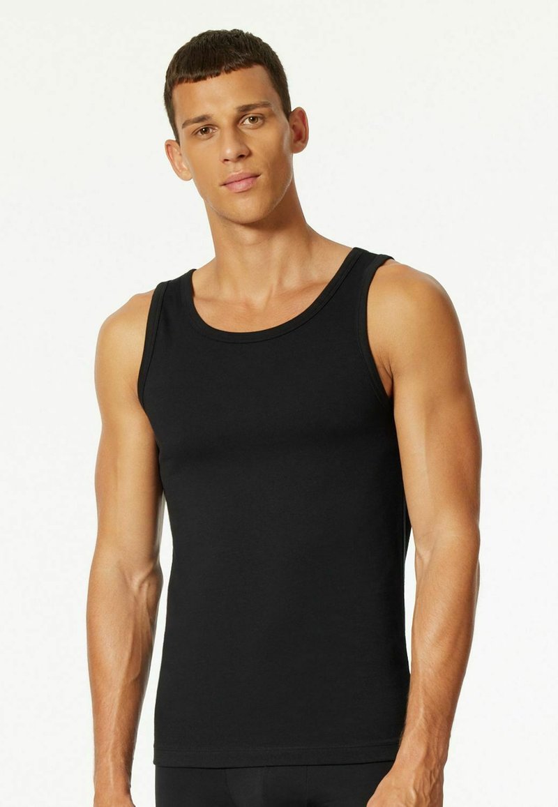 Black tank top made of stretchy, smooth fabric. It features a classic cut with wide shoulder straps and a round neckline.