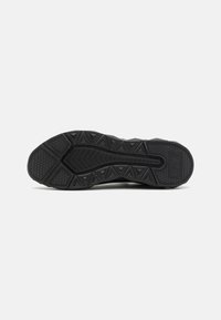 Black athletic shoe sole featuring a textured rubber surface with triangular and geometric treads for enhanced grip and stability.