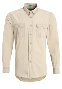 Camicia beige a maniche lunghe realizzata in un misto cotone, con colletto abbottonato, due tasche sul petto e orlo curvo. Dettagli di cuciture semplici.