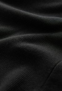 Schwarzer gerippter Stoff mit glatter Textur und sanften Wellen, die feine vertikale Linien und eine reiche, tiefe Farbe aufweisen.