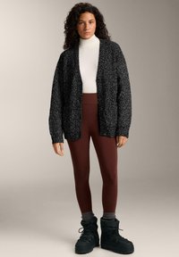 Black and white textured cardigan over a white turtleneck, paired with brown leggings and black boots. Simple design and relaxed fit.
