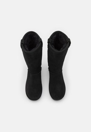 Schwarze Wildlederstiefel mit hohem Design, weicher Innensohle und Schlaufenakzenten hinten für einfachen Einstieg. Glatte Textur und abgerundete Spitzen.