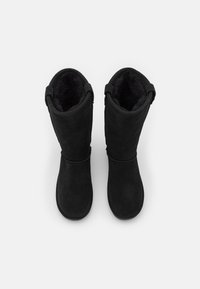 Black suede boots with a tall design, soft inner lining, and back loop accents for ease of wear. Smooth texture and rounded tops.