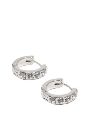 Pequeños pendientes de aro plateados con piedras preciosas transparentes en forma de corazón, distribuidas uniformemente alrededor del borde exterior sobre un fondo blanco.