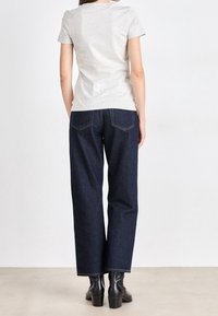 Grå kortärmad t-shirt i kombination med mörkblå högmidjade jeans. Slim fit med rak ben. Slät bomullstextur. Svarta ankelboots.