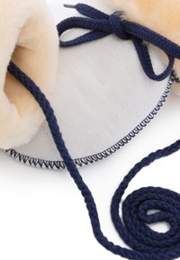 Marineblau geflochtener Krawatte mit weicher beiger Innenausstattung, strukturiertem Wildleder-Außenteil und kontrastierenden marineblauen Nähten am Rand für zusätzliche Details.