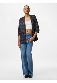 Marineblazer met witte stippen, losse pasvorm, open voorkant, gecombineerd met hoge taille blauwe jeans en zwarte schoenen. Glad textuur, casual ontwerp.