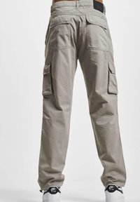 Spodnie cargo w jasnoszarym kolorze z bawełny, z bocznymi kieszeniami, kieszeniami z tyłu oraz luźnym krojem. W komplecie z białymi butami z czarnym logo.