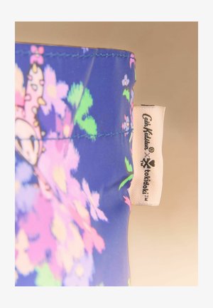 Blauer Stoff mit farbenfrohem Blumenmuster und weißem Etikett mit der Aufschrift "Cath Kidston x tokidoki" auf beigem Hintergrund.