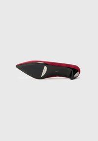 Red suede high-heeled shoe with a pointed toe, black heel cap, and smooth black sole. No visible hardware or patterns.