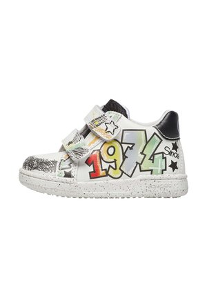 Sneaker bianche con design grafici colorati, che includono "1974" in verde e rosso, con cinturini in velcro e suola maculata.