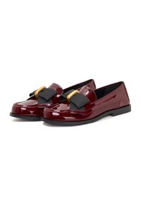 Mocassins bordeaux brillants avec un nœud en tissu noir et des accessoires dorés. Bout arrondi, semelle noire basse et texture lisse.