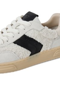 Weiße Sneaker mit einem strukturierten, flauschigen Obermaterial, schwarzen Lederakzenten und cremefarbenen Schnürsenkeln, dicker Gummisohle und dezentem Logodesign.