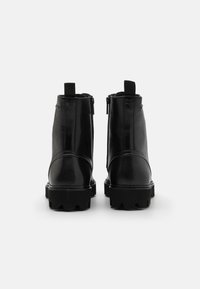 Bottes noires en cuir à la cheville avec une finition lisse, des fermetures éclair sur les côtés et des semelles en caoutchouc épaisses dotées de profondes sculptures pour une bonne adhérence et une stabilité accrue.